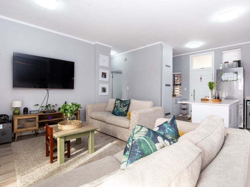 An open-plan living area featuring laminate flooring, recessed lighting, and a functional kitchen island, creating a bright and cohesive living space.