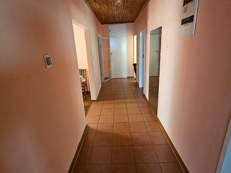 A functional hallway featuring tiled flooring and a timber-paneled ceiling, providing access to multiple rooms within the home.