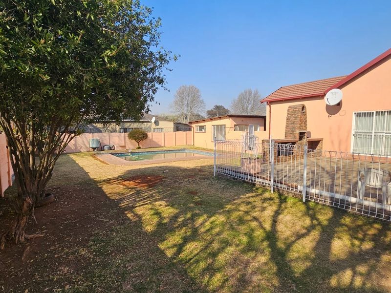 Rear garden featuring a swimming pool, paved patio area with a built-in brick braai, and perimeter walling.
