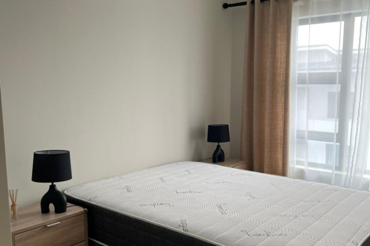 A well-maintained bedroom featuring neutral wall tones, tiled flooring, and a ceiling fan, providing a clean and functional living space.