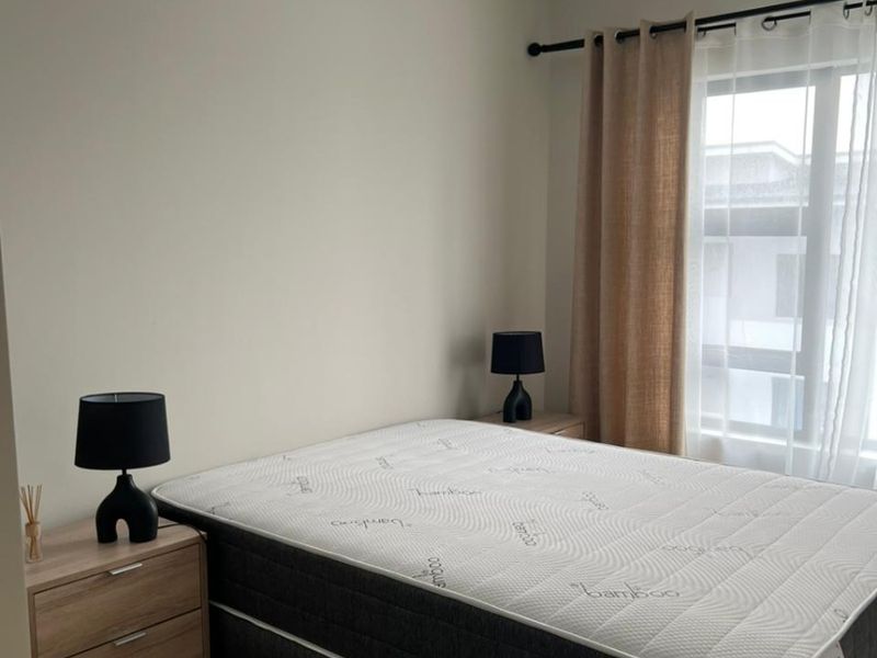 A well-maintained bedroom featuring neutral wall tones, tiled flooring, and a ceiling fan, providing a clean and functional living space.