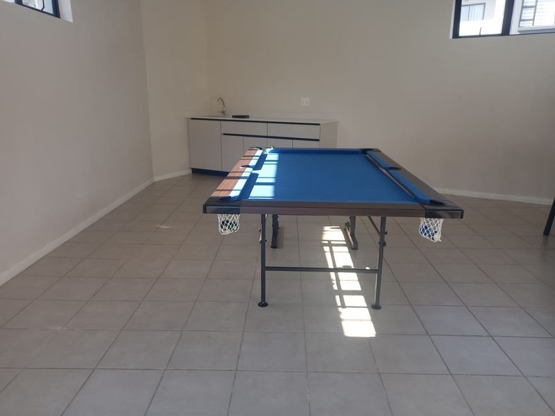A utility space featuring tiled flooring and built-in cabinetry with a sink, currently utilized as a recreational area.
