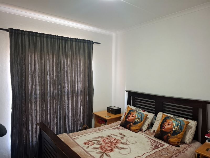 A standard bedroom featuring neutral walls, cove cornicing, and a curtain rod installed over the window area.