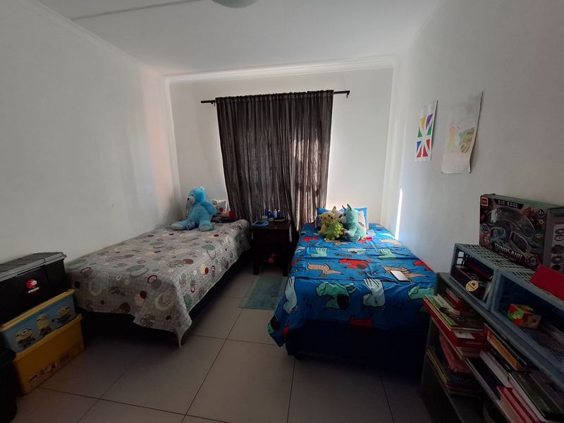 A functional bedroom featuring tiled flooring and a window with a curtain rod, providing a neutral space ready for personalization.