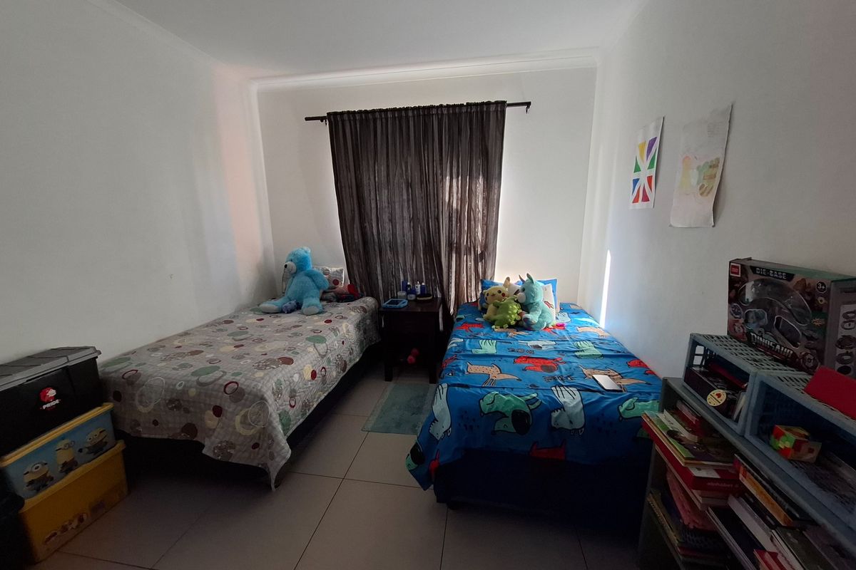 A functional bedroom featuring tiled flooring and a window with a curtain rod, providing a neutral space ready for personalization.