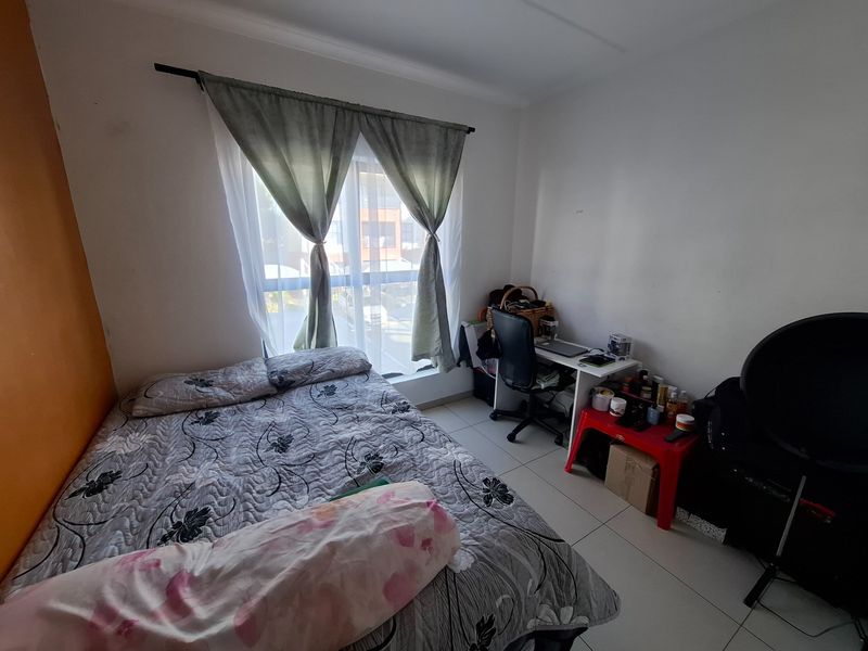A standard bedroom featuring tiled flooring and a window with a curtain rod, providing a functional space for rest or study.