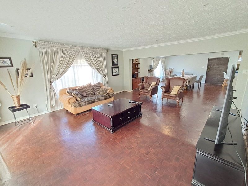 Spacious open-plan living and dining area featuring traditional parquet flooring, textured ceilings, and a built-in shelving unit.