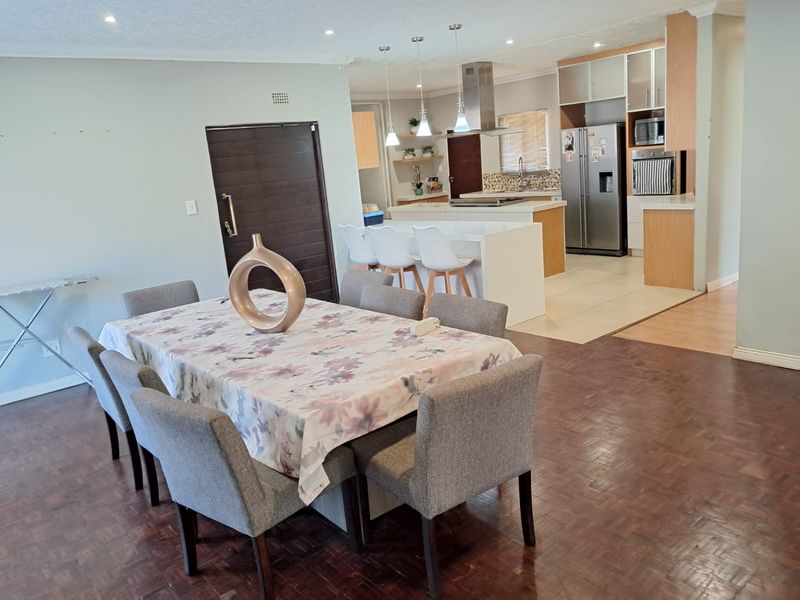 Open-plan living and dining area featuring a modern kitchen with a central island, built-in appliances, and a combination of parquet and tiled flooring.