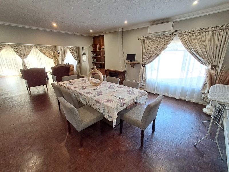 Spacious open-plan living and dining area featuring parquet flooring, a brick fireplace, built-in shelving, and a split-system air conditioner.