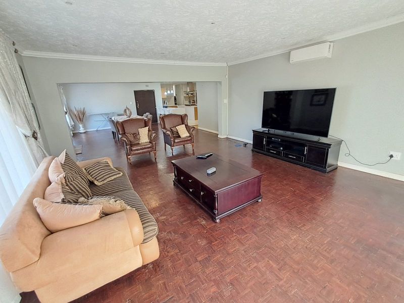 Spacious open-plan living area featuring traditional parquet flooring, coved ceilings, and a wall-mounted air conditioning unit.