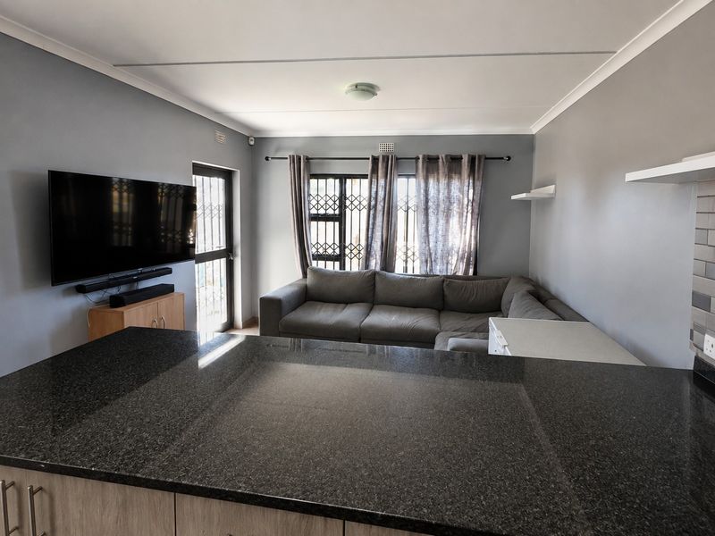 Open plan living area featuring a granite kitchen island, security gates, and neutral grey walls, creating a functional and connected living space.