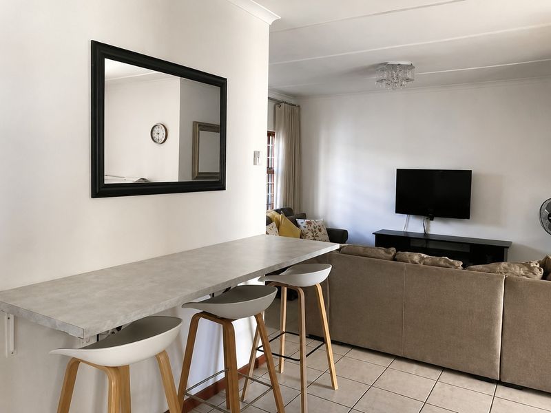 Open plan living area featuring a breakfast bar with stone-look countertop and tiled flooring, seamlessly connecting to the lounge space.
