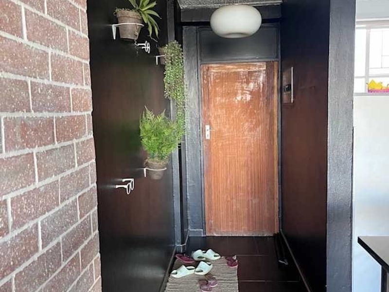 A narrow hallway featuring dark painted walls, tiled flooring, a textured ceiling, and a wooden entrance door.