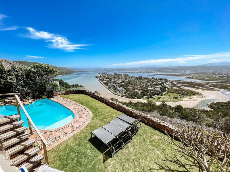 Outdoor pool area featuring a swimming pool, stone retaining wall, and expansive elevated views over the estuary and surrounding landscape.