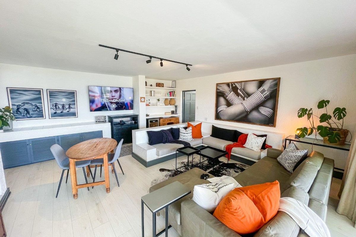 Spacious living room featuring built-in cabinetry, integrated shelving, modern track lighting, and light-toned laminate flooring in a well-maintained open-plan layout.