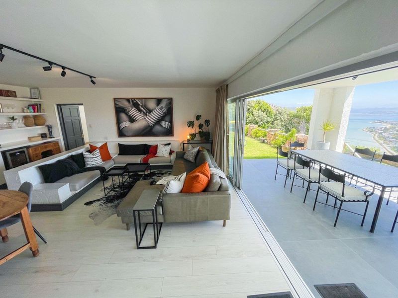 Spacious open-plan living area featuring modern track lighting, built-in shelving, and large sliding glass doors that open onto a scenic outdoor patio.