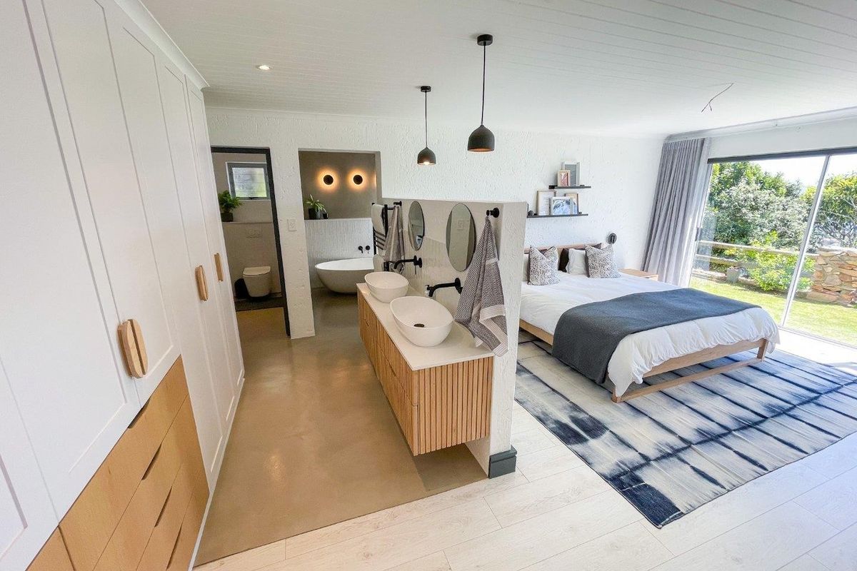 Spacious master bedroom featuring an open-plan ensuite with a double vanity, freestanding bathtub, and direct access to the garden through sliding glass doors.