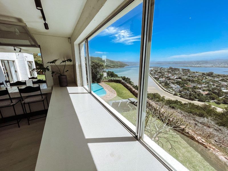 A bright interior space featuring a large picture window with expansive panoramic views of the estuary, coastline, and surrounding landscape.