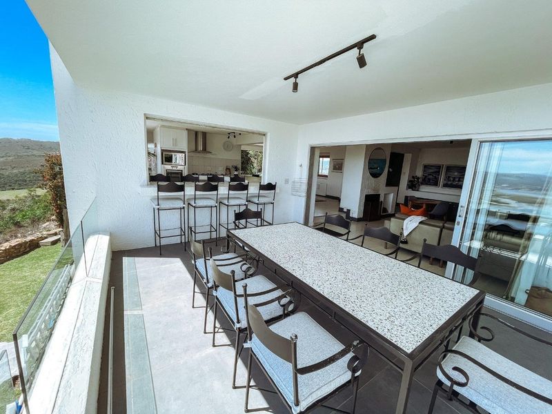 Spacious covered patio featuring a glass balustrade, tiled flooring, and a convenient pass-through window connecting to the kitchen area.