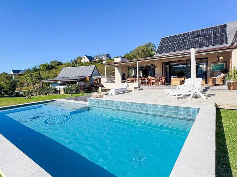 A well-maintained swimming pool with tiled coping, adjacent to a spacious timber deck and covered patio area featuring roof-mounted solar panels.