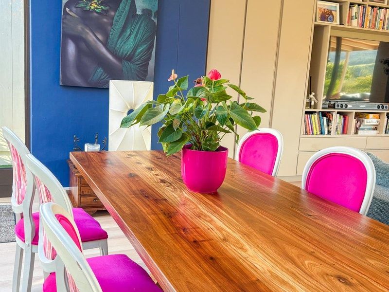 A vibrant dining area featuring custom built-in cabinetry with integrated shelving, timber flooring, and a statement decorative chandelier.