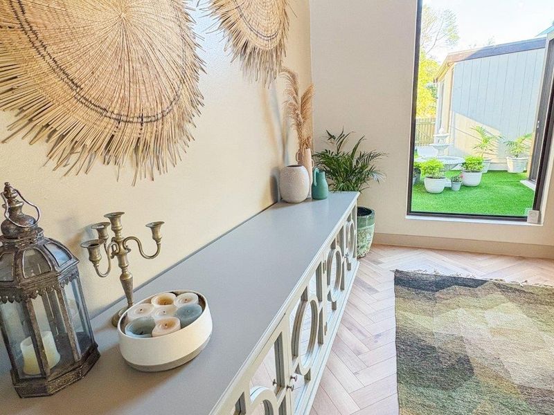 Bright living area featuring elegant herringbone timber flooring, a high vaulted timber ceiling, and a large window providing natural light and garden views.