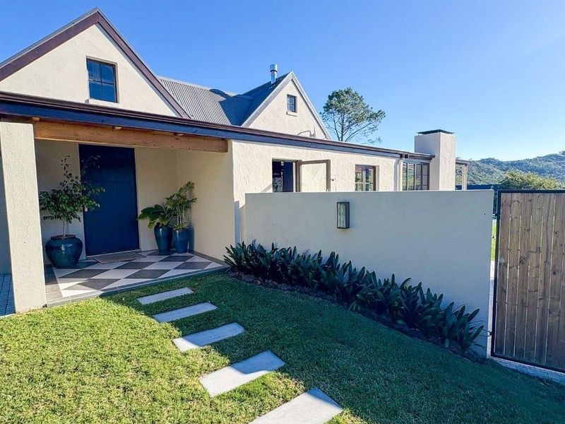 A well-maintained front entrance featuring a covered porch, tiled flooring, and a landscaped garden with a stone pathway.