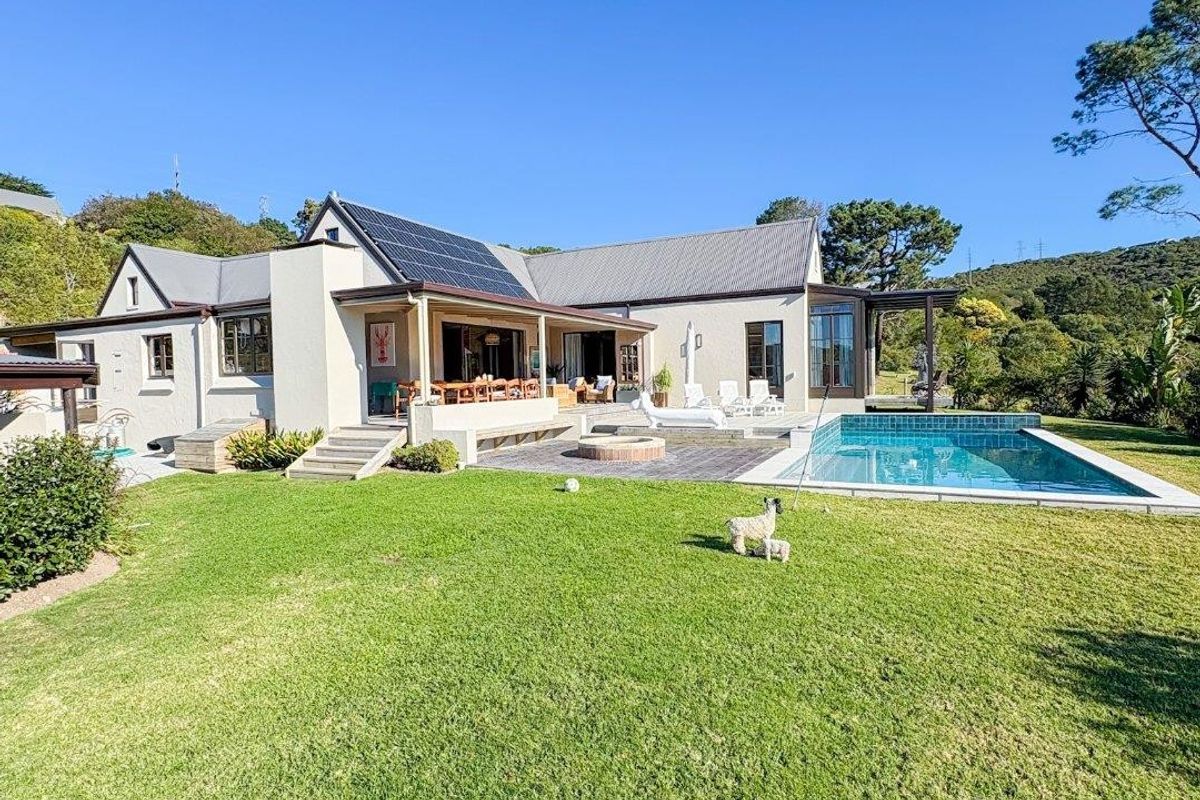 Rear view of the property featuring a well-maintained lawn, a swimming pool, a paved patio area with a fire pit, and a covered veranda.