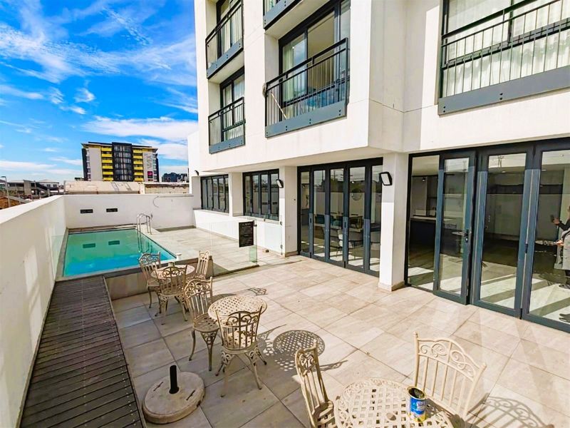 A modern outdoor terrace featuring a swimming pool, tiled patio area, and seamless access to the interior through large bi-fold doors.