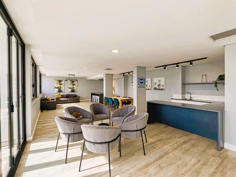 Spacious open-plan living area featuring a modern kitchen with island, laminate flooring, and large sliding glass doors providing ample natural light.