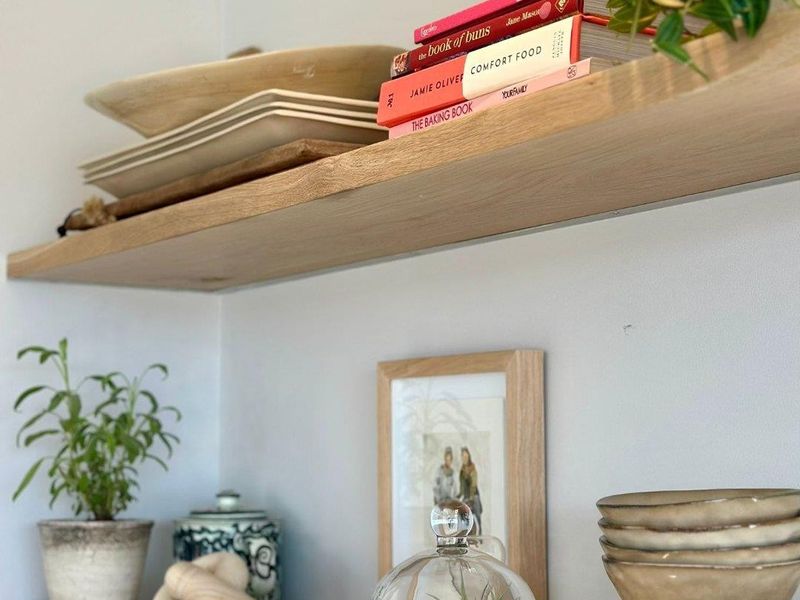 Close-up view of modern timber floating shelves mounted on a neutral wall, providing functional storage and display space.