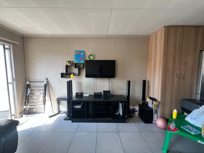 A living room area featuring tiled flooring, a built-in wooden cupboard, and a sliding door providing access to the exterior.
