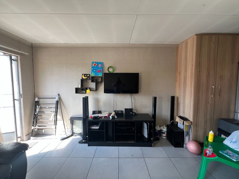Living room area featuring neutral wall finishes, tiled flooring, and a built-in wooden wardrobe for storage.