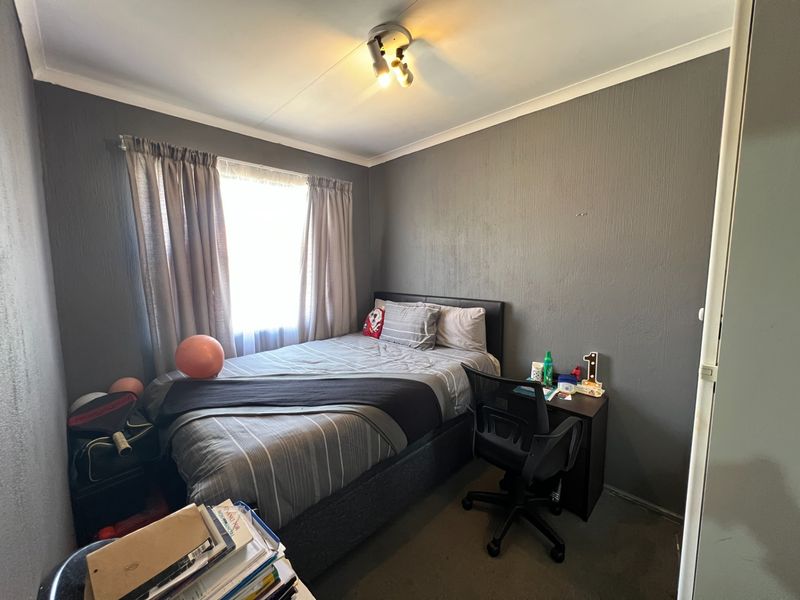 A standard bedroom featuring dark grey textured walls, a ceiling light fixture, and a window with curtain rod.