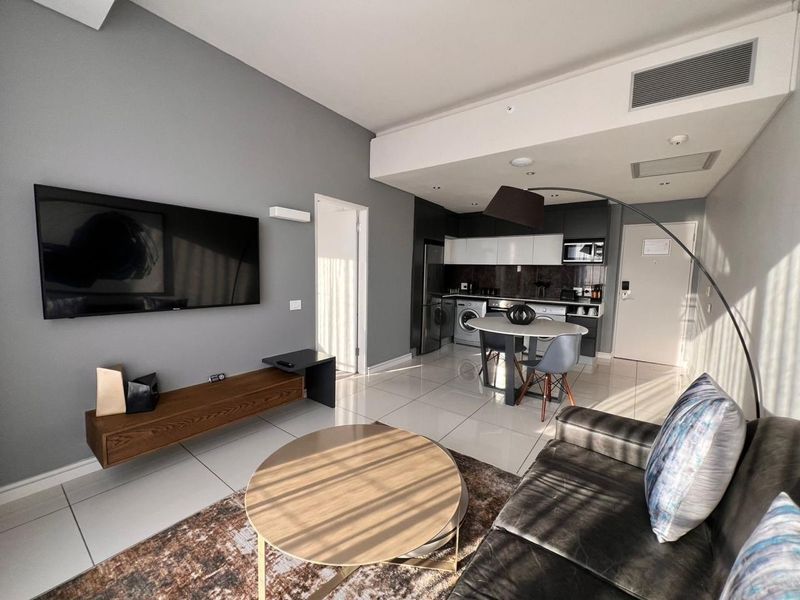 Modern open-plan living area featuring a sleek kitchen with built-in cabinetry, tiled flooring, and integrated ducted air conditioning.