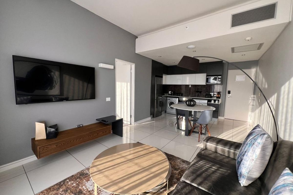 Modern open-plan living area featuring a sleek kitchen with built-in cabinetry, tiled flooring, and integrated ducted air conditioning.