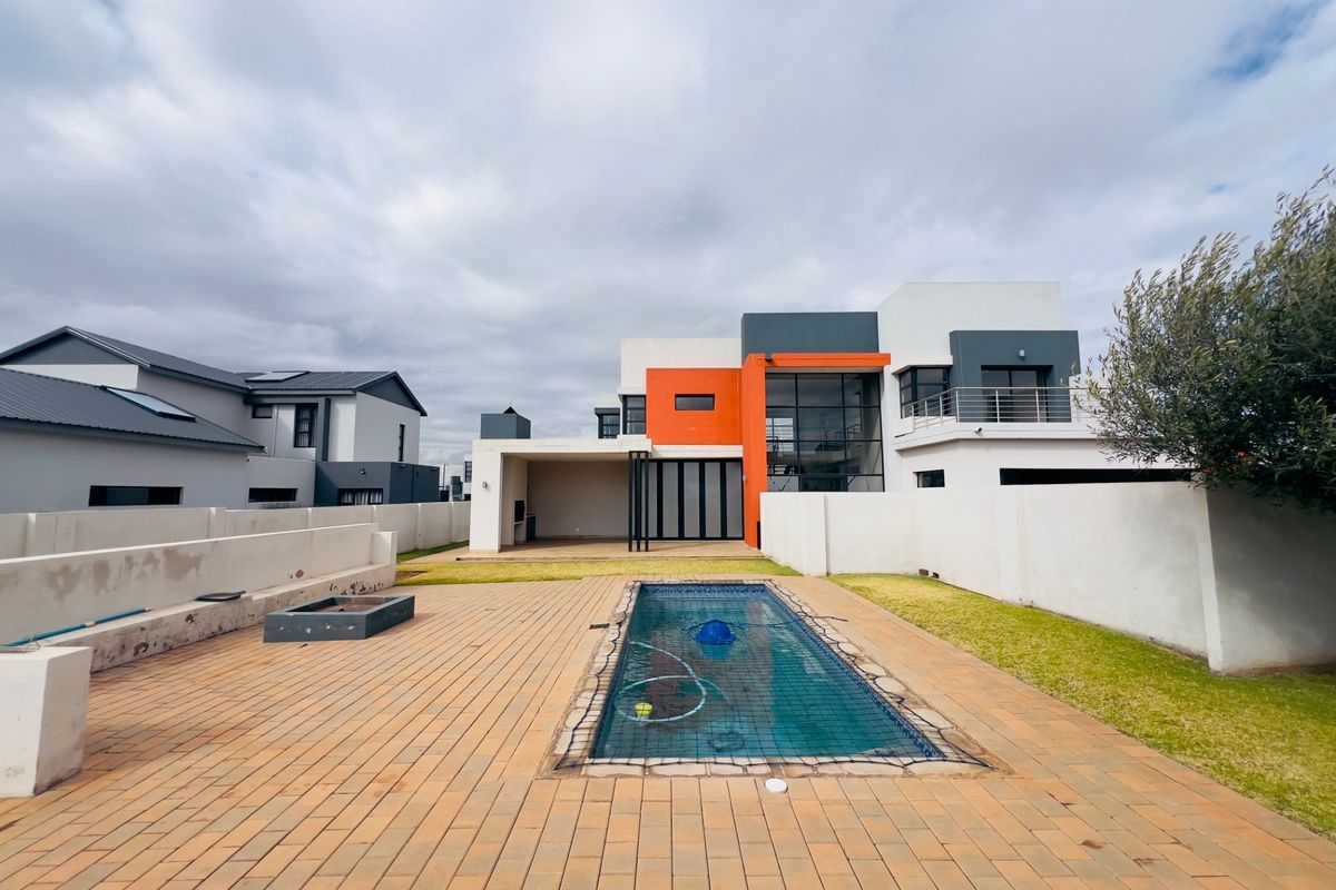 Rear view of a modern two-story house featuring a swimming pool, paved patio area, and a covered outdoor entertainment space.