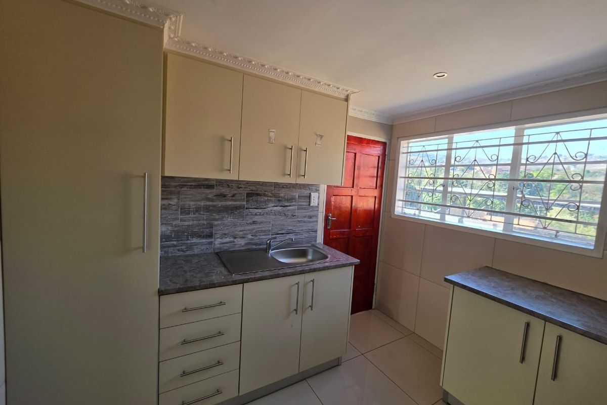 A functional kitchen featuring built-in cabinetry, laminate countertops, a stainless steel sink, and tiled flooring, offering a clean and practical workspace.