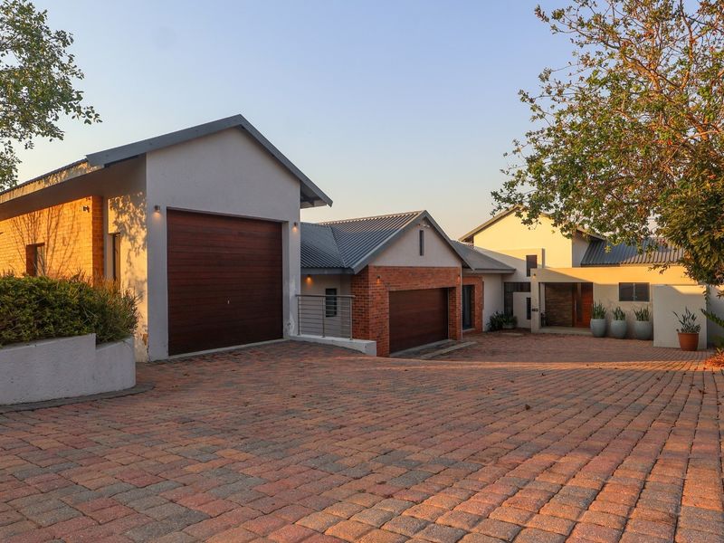 A well-maintained front exterior view of a modern house featuring a paved driveway, double garage, and attractive brick and render facade.