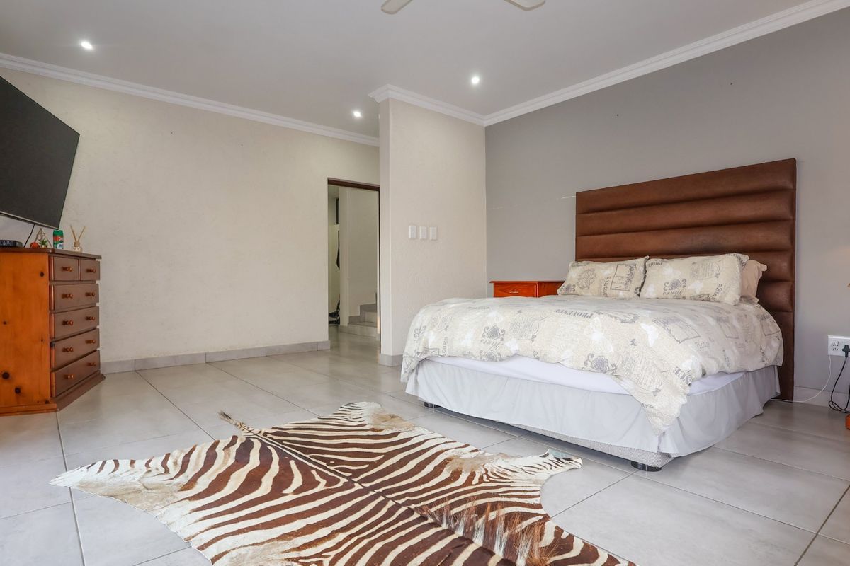 Spacious bedroom featuring neutral tiled flooring, recessed ceiling lighting, and a ceiling fan, offering a clean and functional living space.