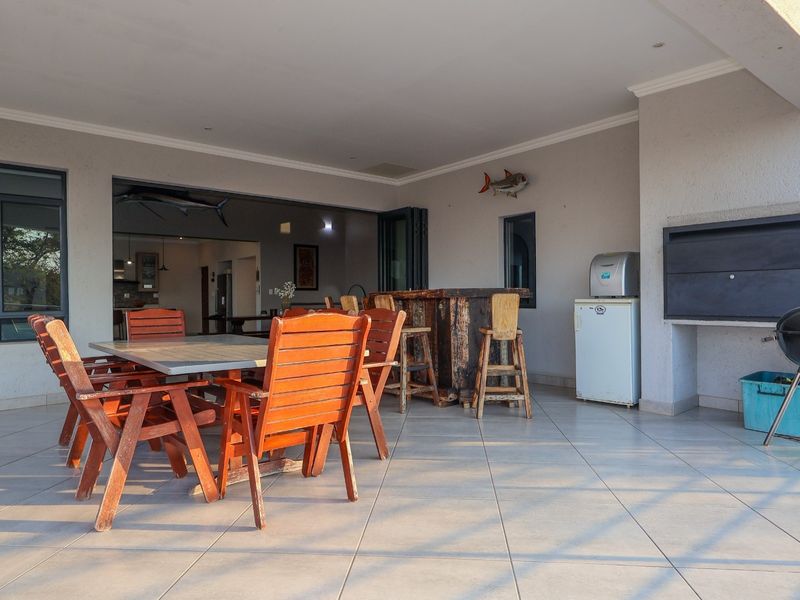 Spacious covered patio featuring tiled flooring, recessed lighting, and a built-in braai, providing an ideal space for outdoor entertaining.