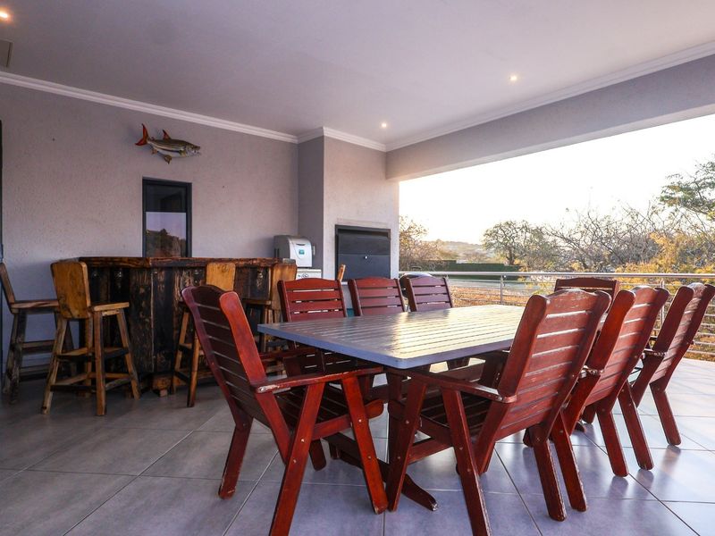Spacious covered patio featuring a built-in braai, tiled flooring, and stainless steel balustrades, offering an ideal space for outdoor entertaining.