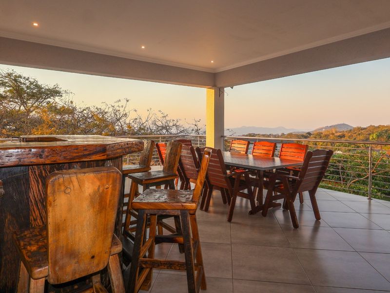 Spacious covered patio featuring a built-in bar, tiled flooring, and panoramic views, perfect for outdoor entertaining.