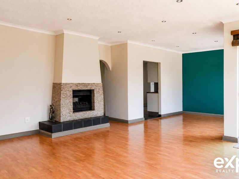 Spacious living area featuring laminate flooring, a built-in fireplace with stone detailing, and direct access to the outdoor area through a sliding glass door.