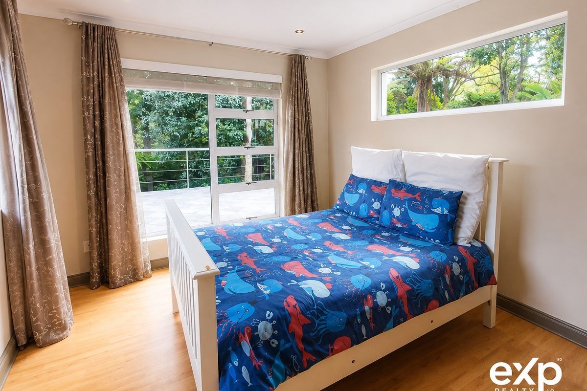A bright bedroom featuring laminate flooring, recessed lighting, and a sliding glass door providing access to an outdoor area.