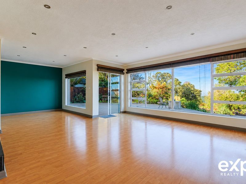 Spacious, light-filled living area featuring laminate flooring, recessed lighting, and large windows with direct access to the outdoor patio and garden.