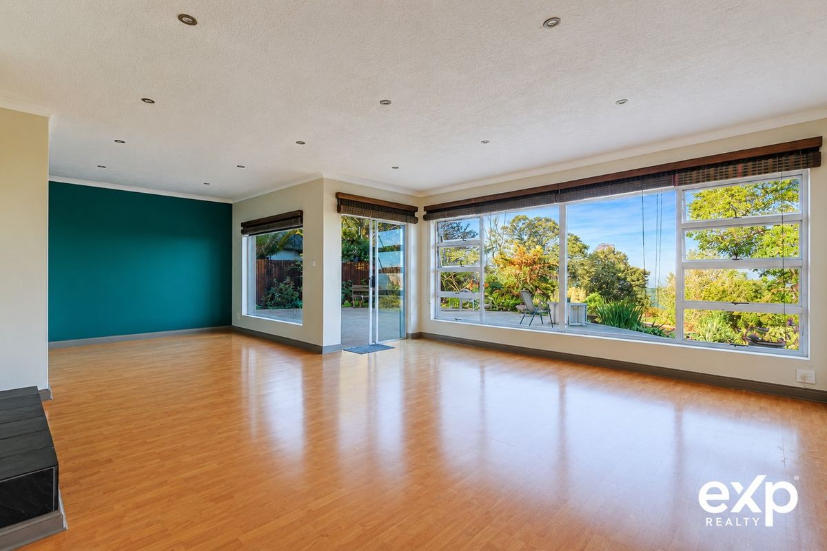 Spacious, light-filled living area featuring laminate flooring, recessed lighting, and large windows with direct access to the outdoor patio and garden.