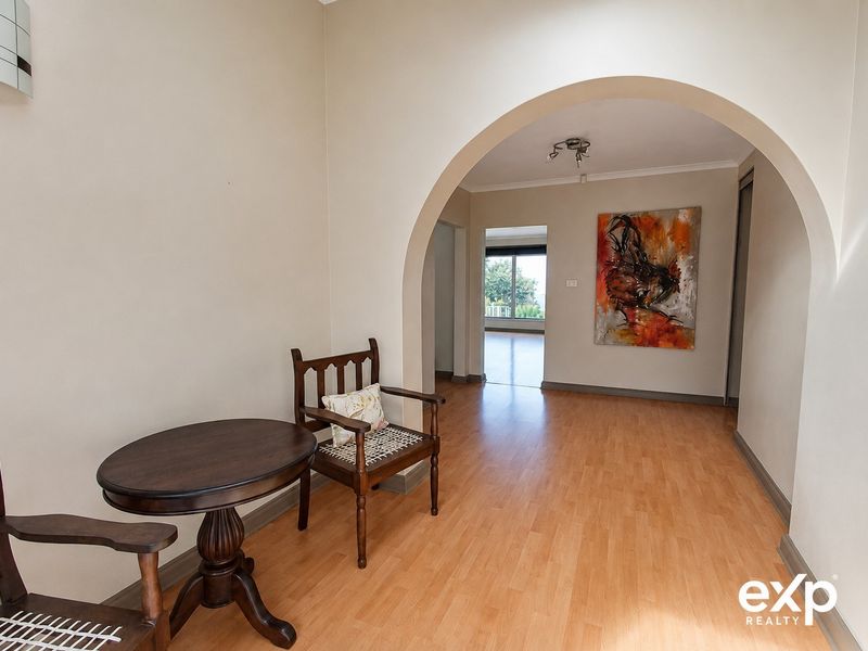 A bright hallway featuring laminate flooring and a distinctive arched architectural detail leading into the main living area.
