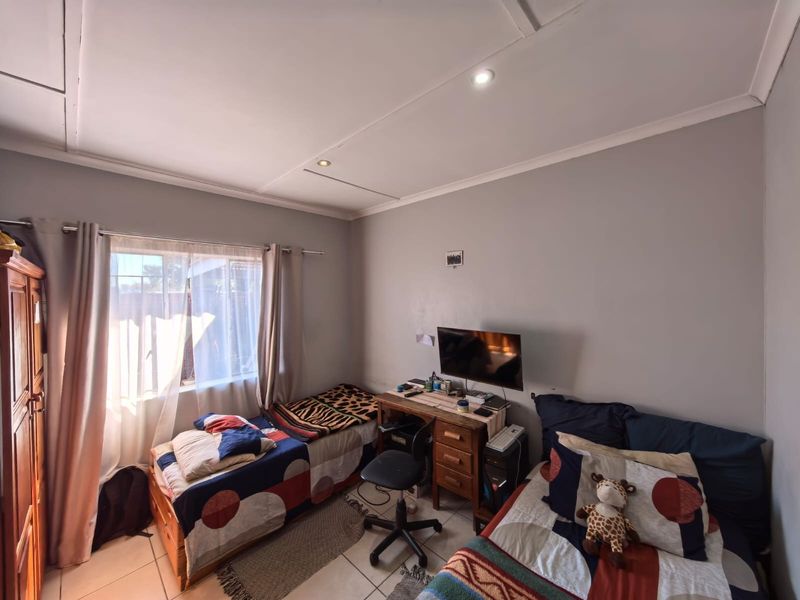 A functional bedroom featuring tiled flooring, recessed downlighting, and a window with curtain rails, providing a comfortable space for rest.