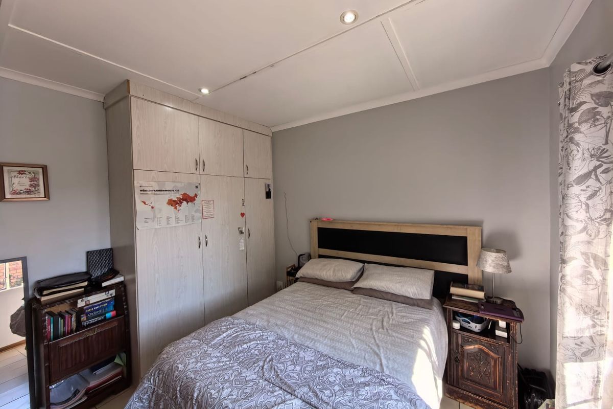 A functional bedroom featuring built-in wardrobes, tiled flooring, and recessed downlighting, offering a neutral base for personalization.